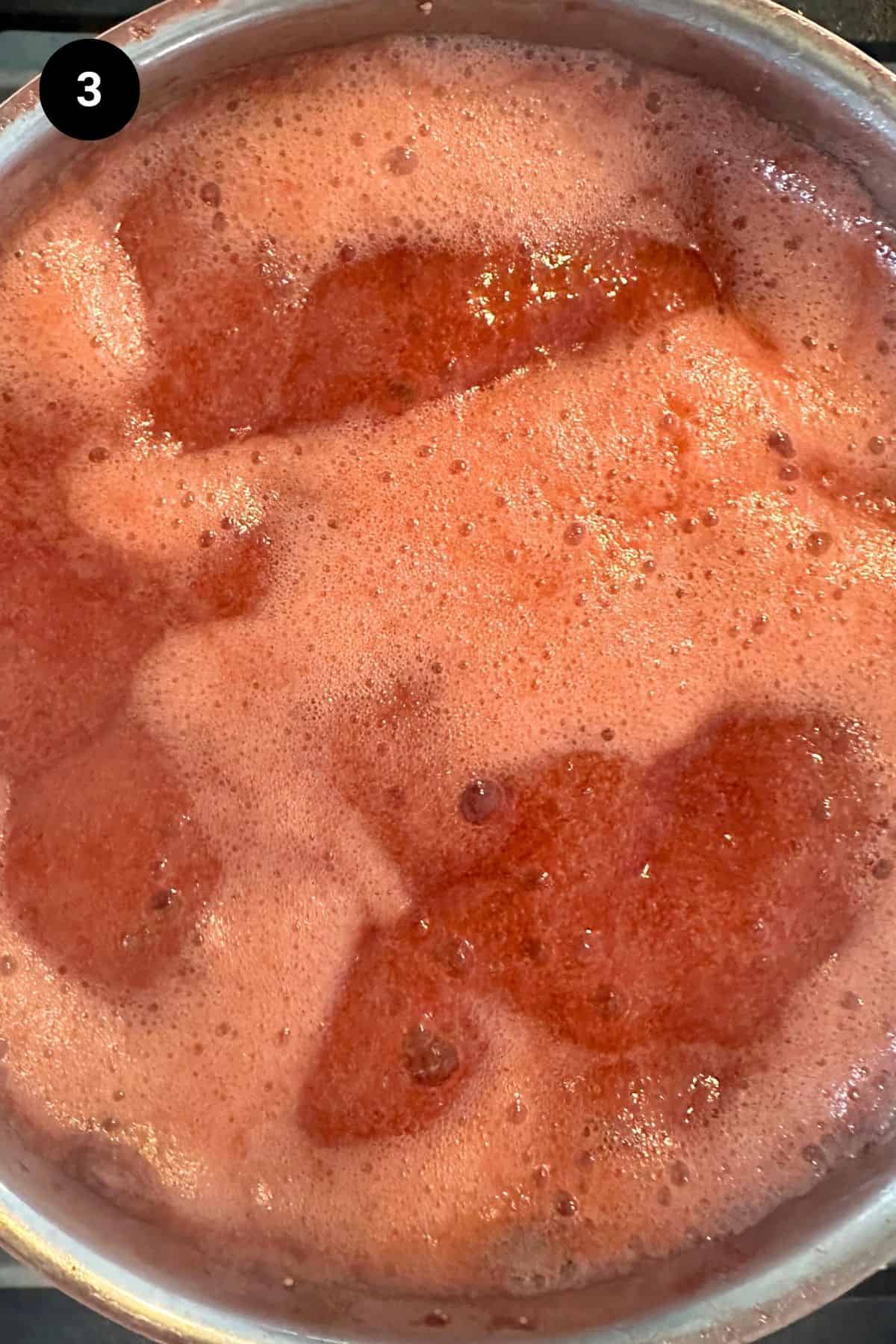 Strawberry puree reducing in a saucepan.