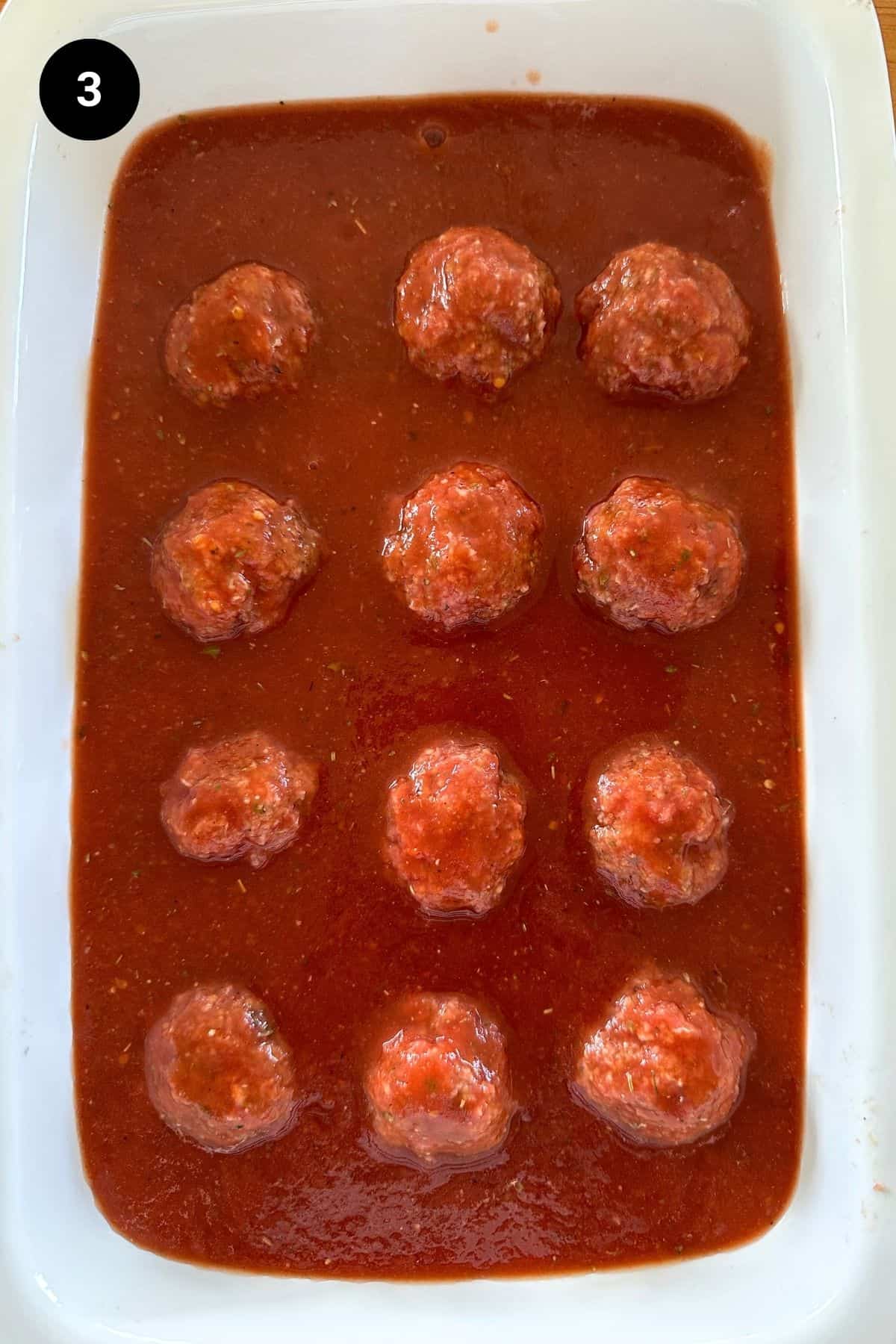Meatballs in a white casserole dish before being baked.