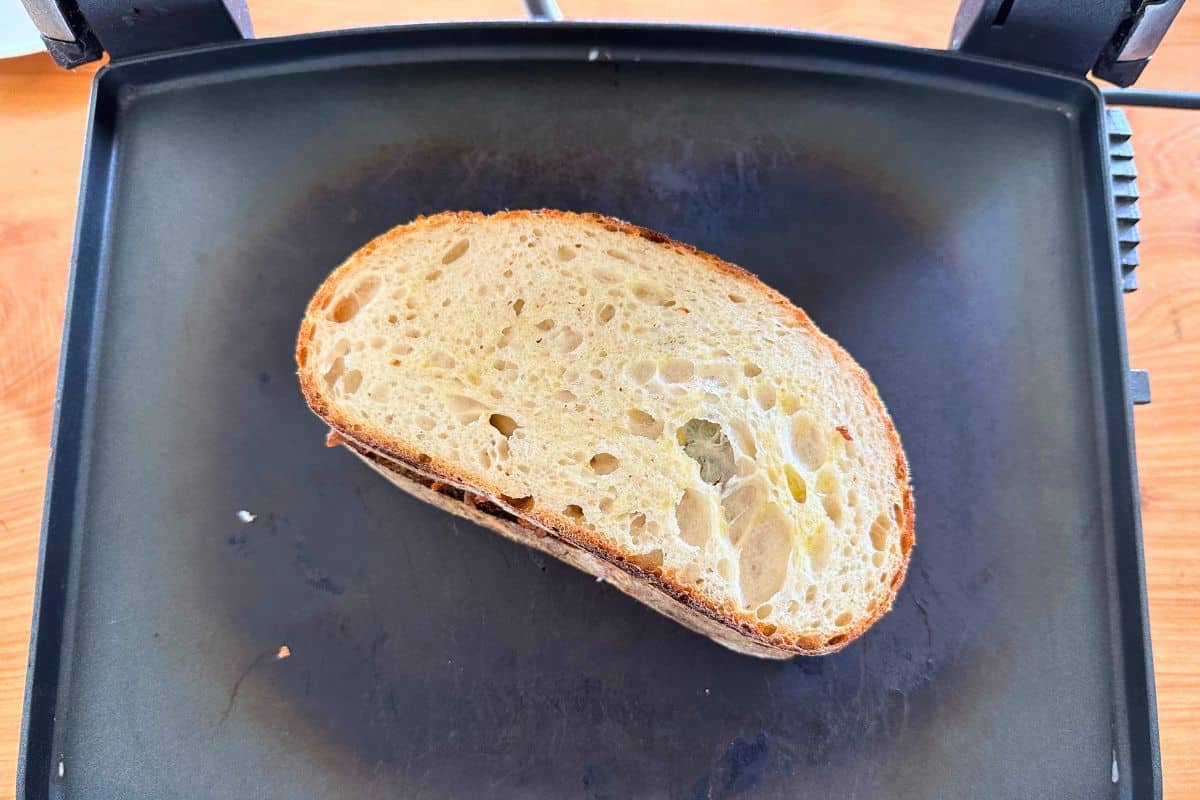 Filled sandwich in sandwich press, ready to be grilled.