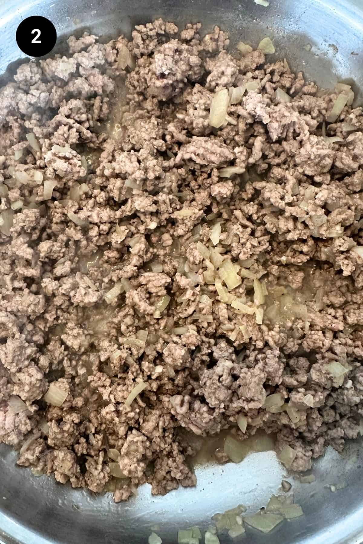 Cooked ground meat in a large pan.