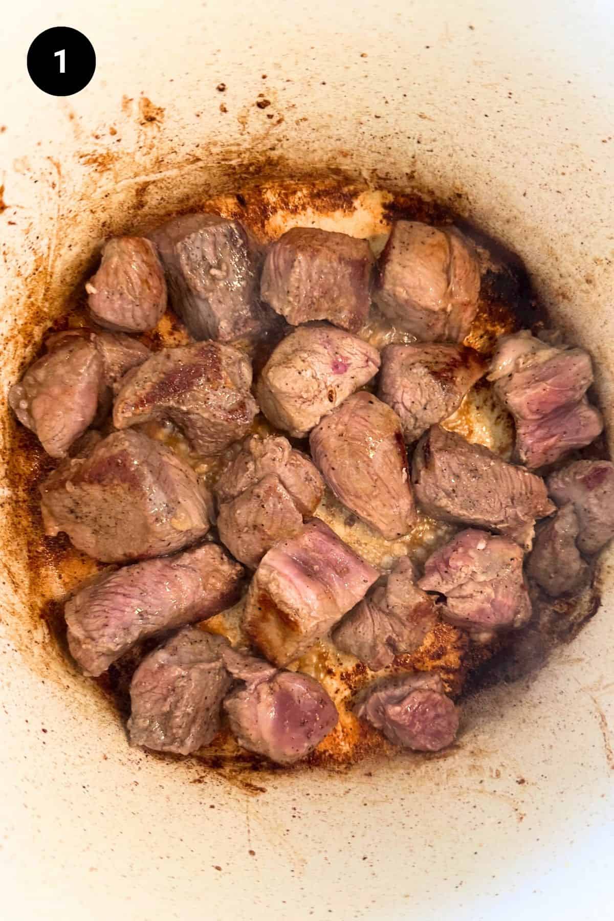 Browned diced lamb in a pot.
