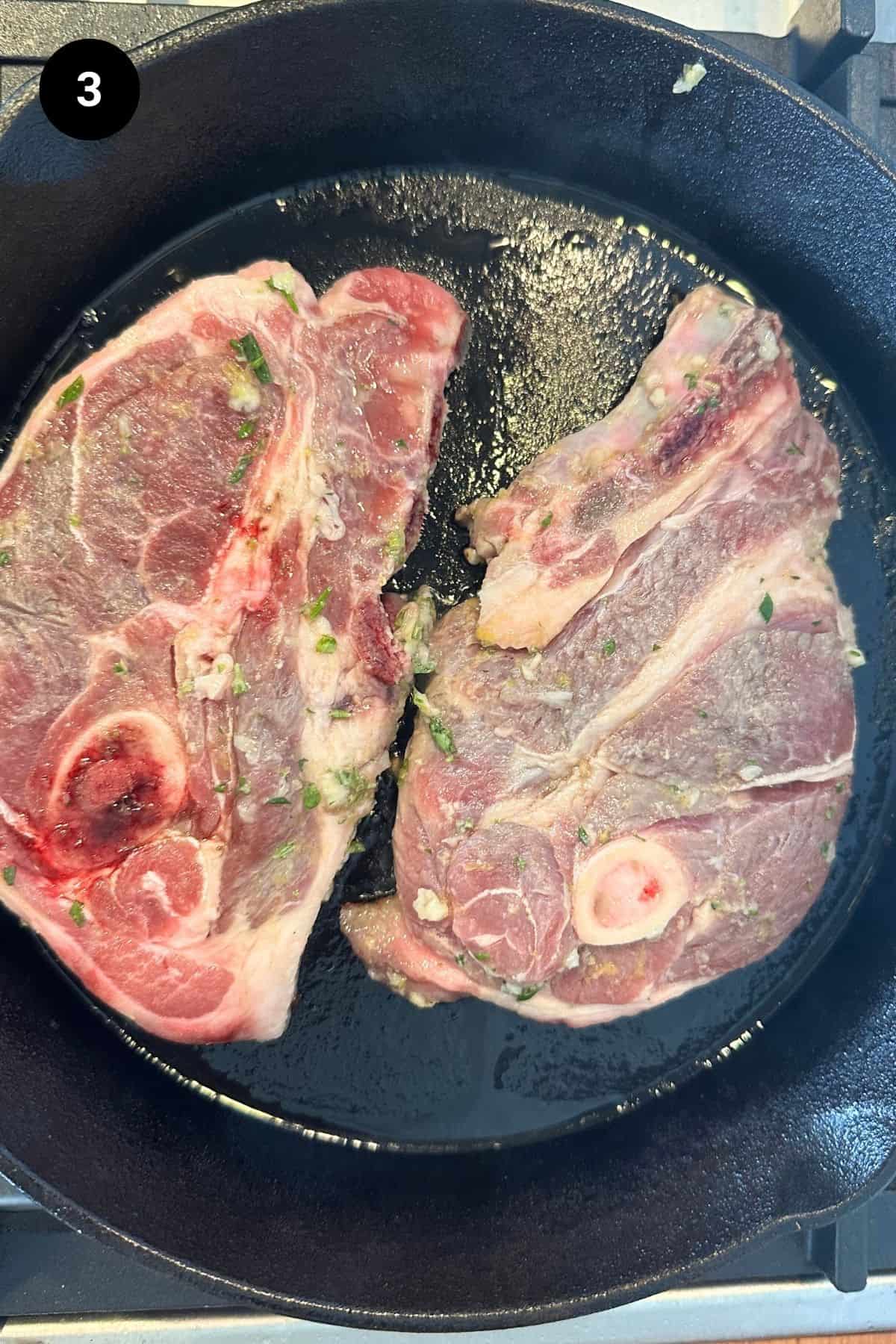 Lamb shoulder chops in a cast iron skillet.