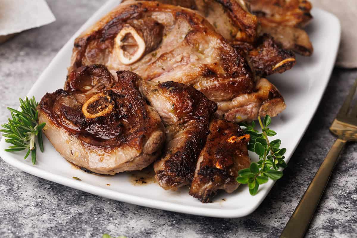 Pan-fried lamb shoulder chops on a white plate.