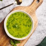 Mint chimichurri sauce in a small bowl on a wooden board.