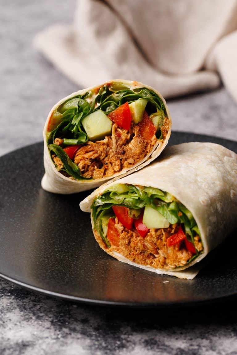 Chicken wrap cut in half on a black plate.