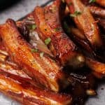 Lamb ribs on a parchment paper lined black slate.