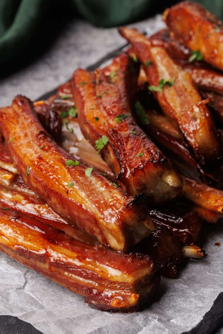 Lamb ribs on a parchment paper lined black slate.