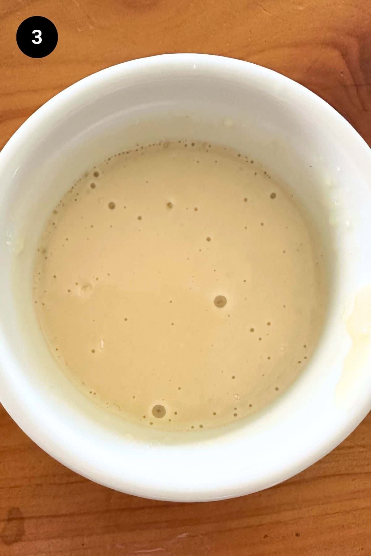 Roast juices mixed with flour in a white ceramic bowl.