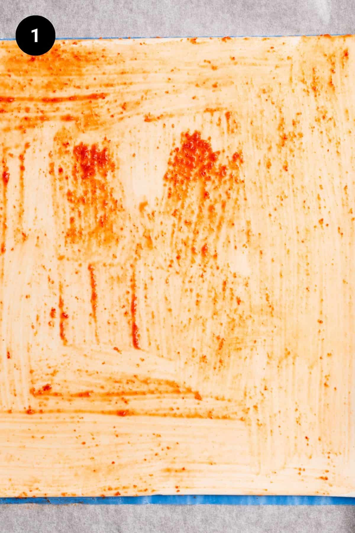 Puff pastry sheet covered in sriracha sauce.