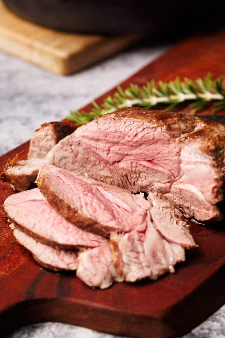 Lamb roast sliced up on a wooden board.