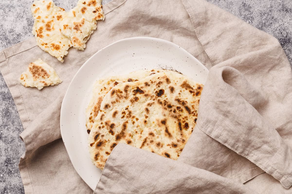 Flatbreads on a plate wrapped in a tea towel.