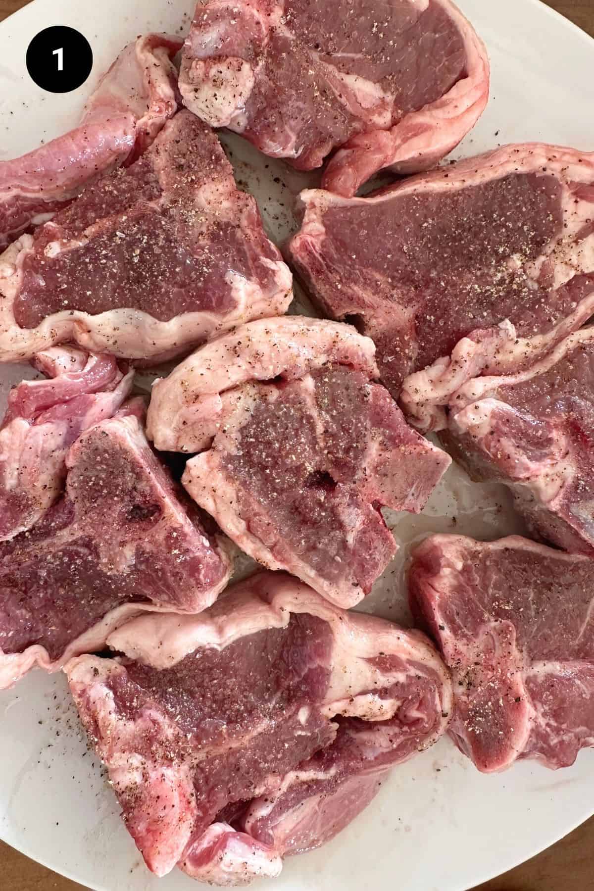 Seasoned lamb chops on a plate.