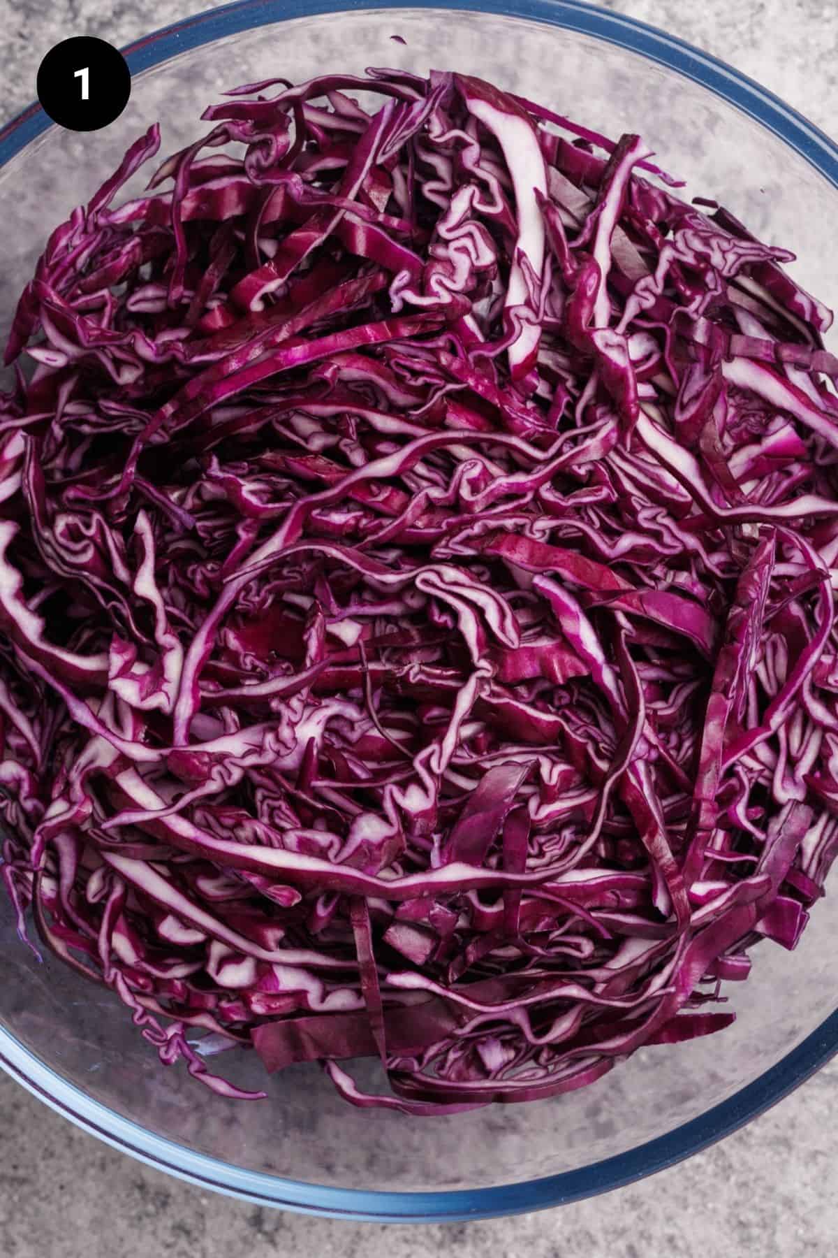 Finely sliced red cabbage in a large glass bowl.