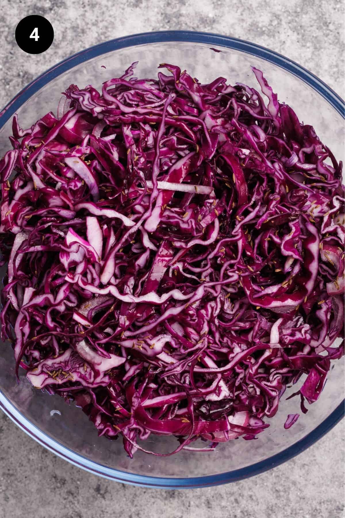 Dressed red cabbage salad in a large glass bowl.