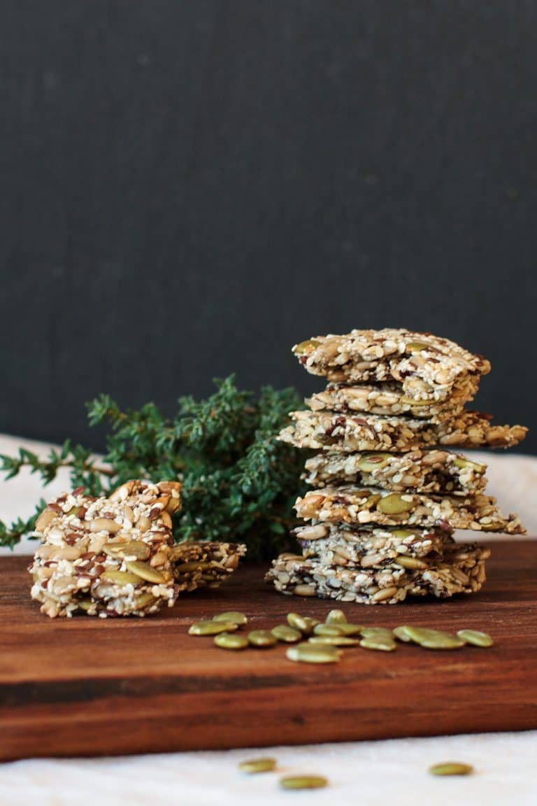 Stack of seed crackers on a wooden board.