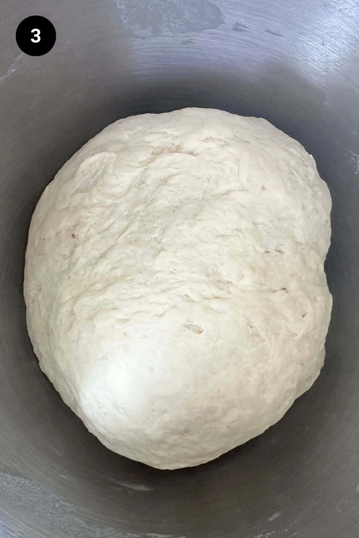 Risen dough in metal bowl.