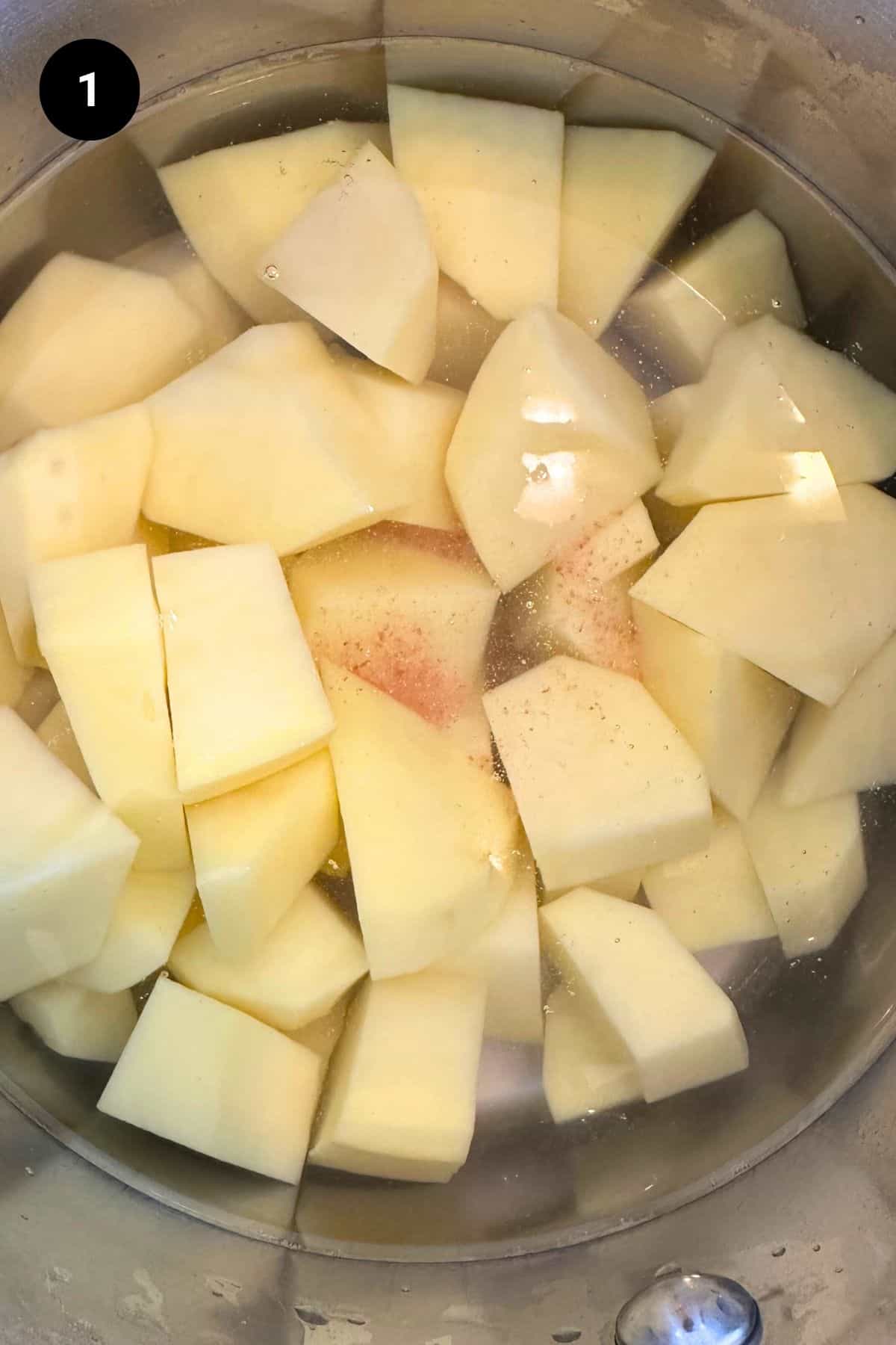 Raw potatoes in a pot with water.