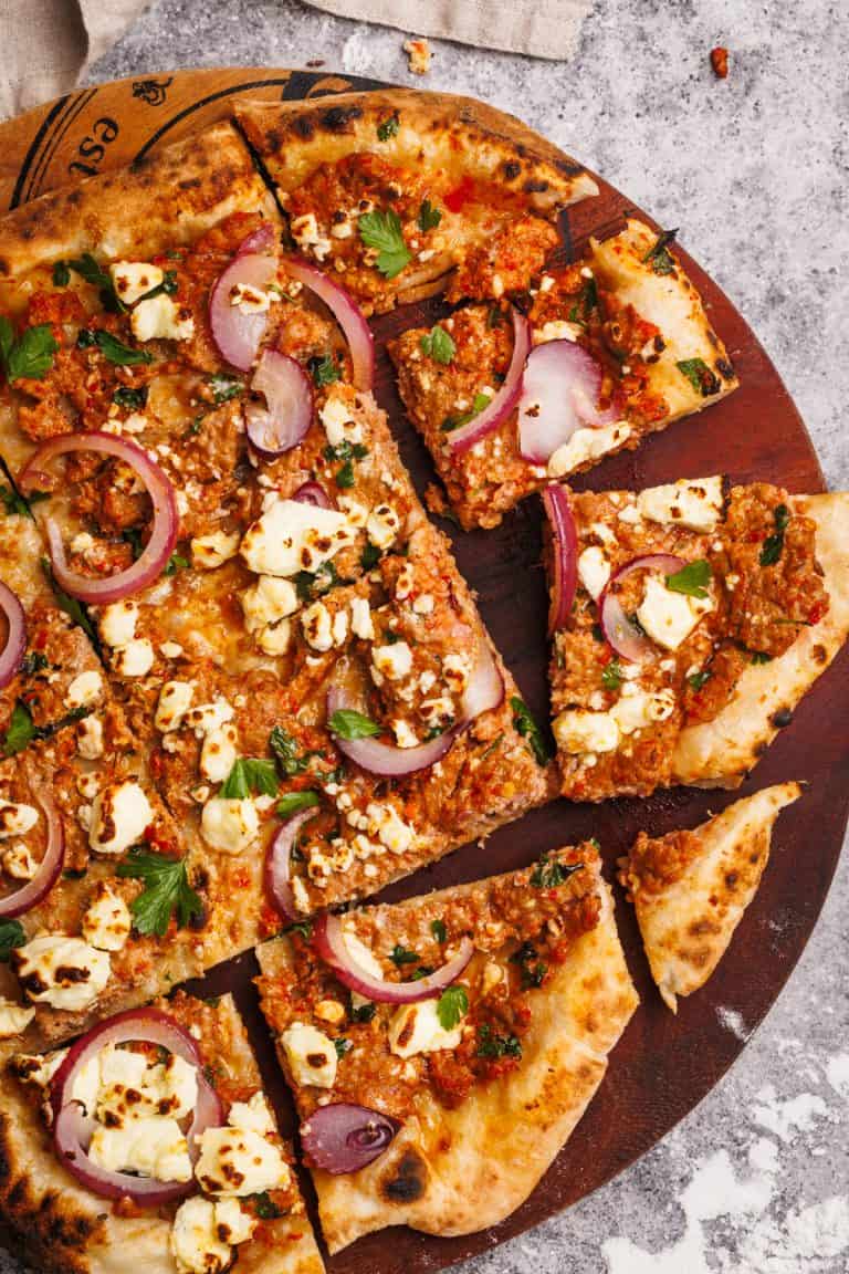 Sliced up Turkish pizza on a wooden board.