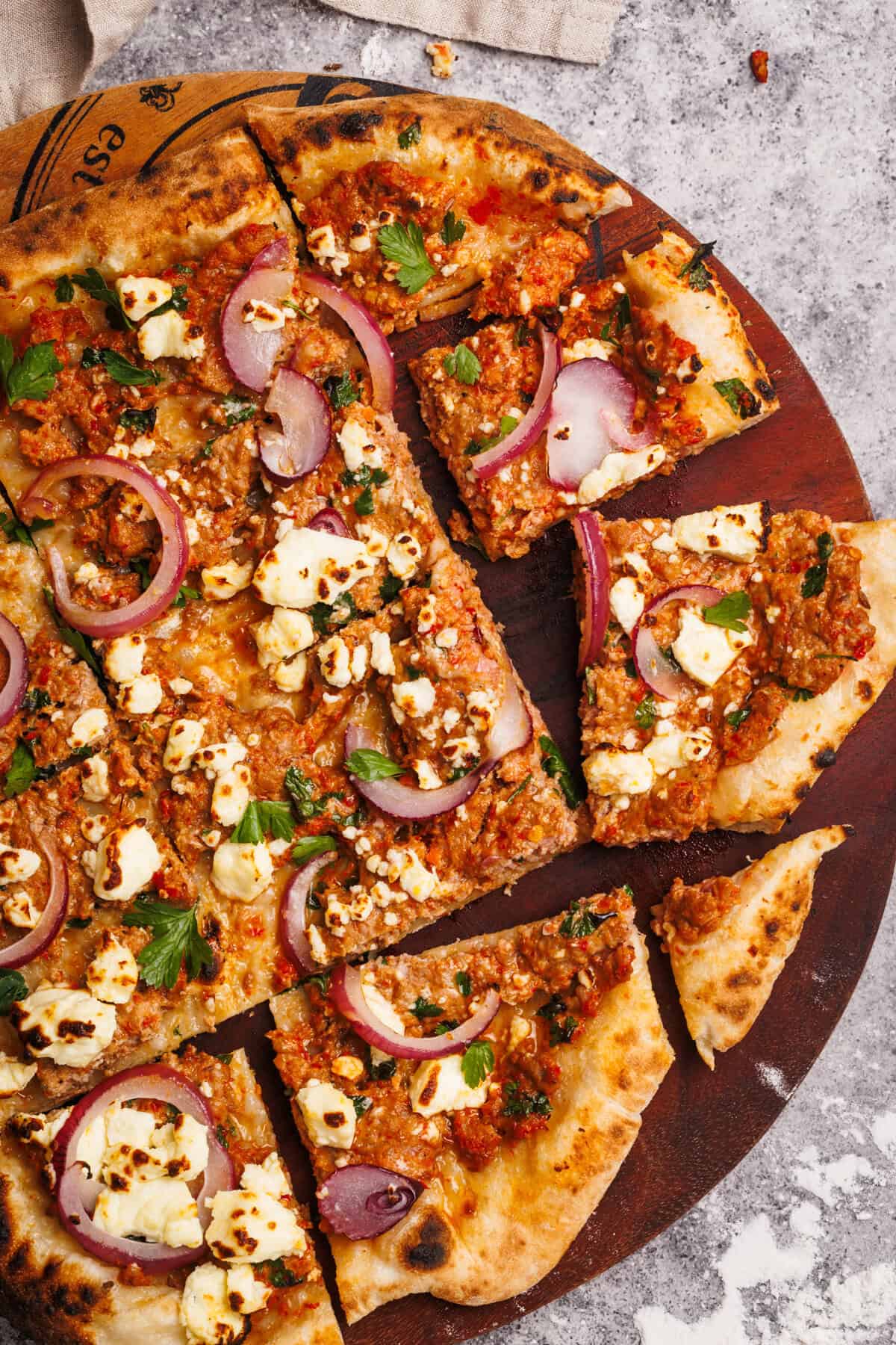 Sliced up Turkish pizza on a wooden board.