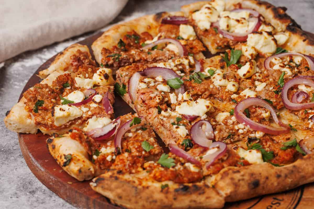Sliced up Turkish pizza on a wooden board.
