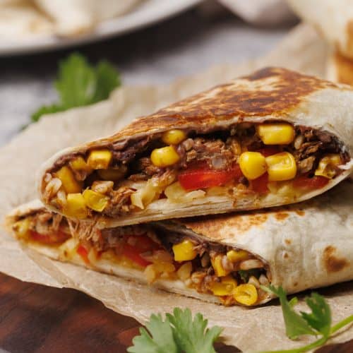 Birria burrito cut in half on a wooden board.
