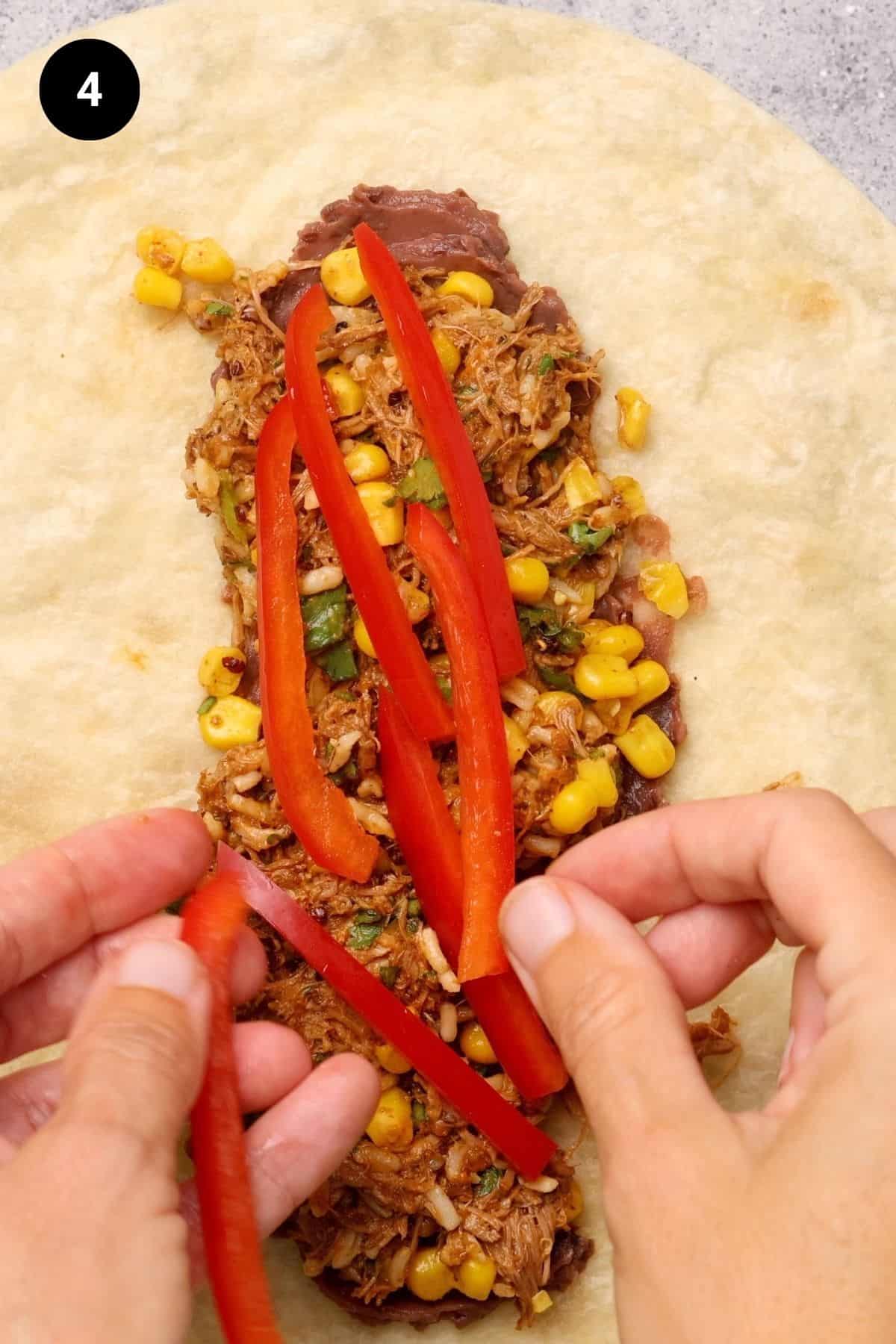 Red peppers being added to burrito filling.