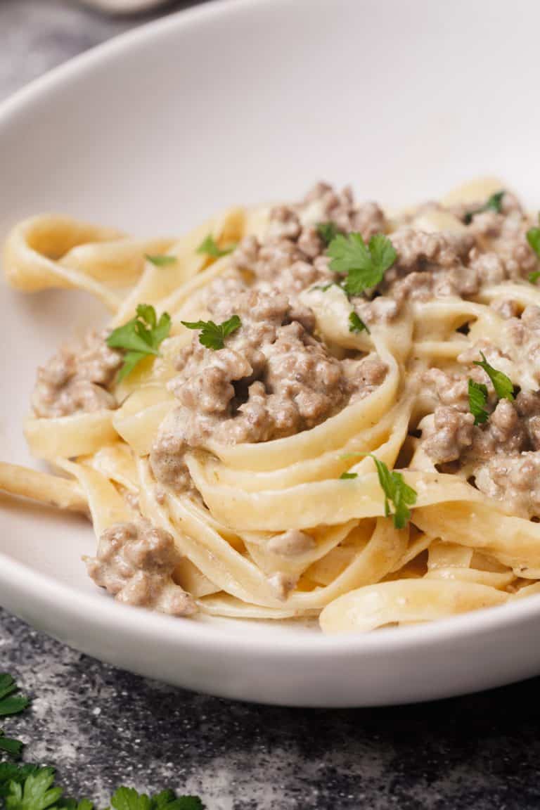 Hamburger Alfredo pasta in white bowl.