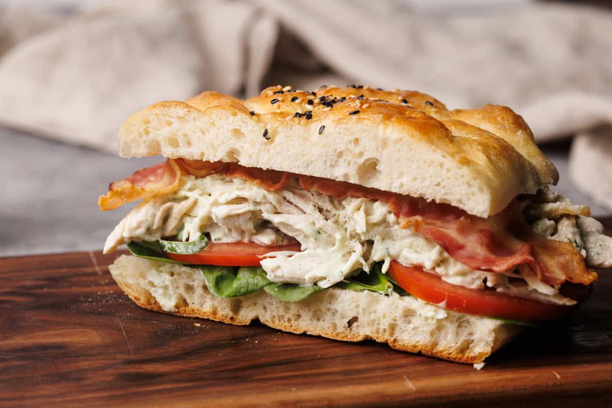 Chicken bacon ranch sandwich on a wooden board.