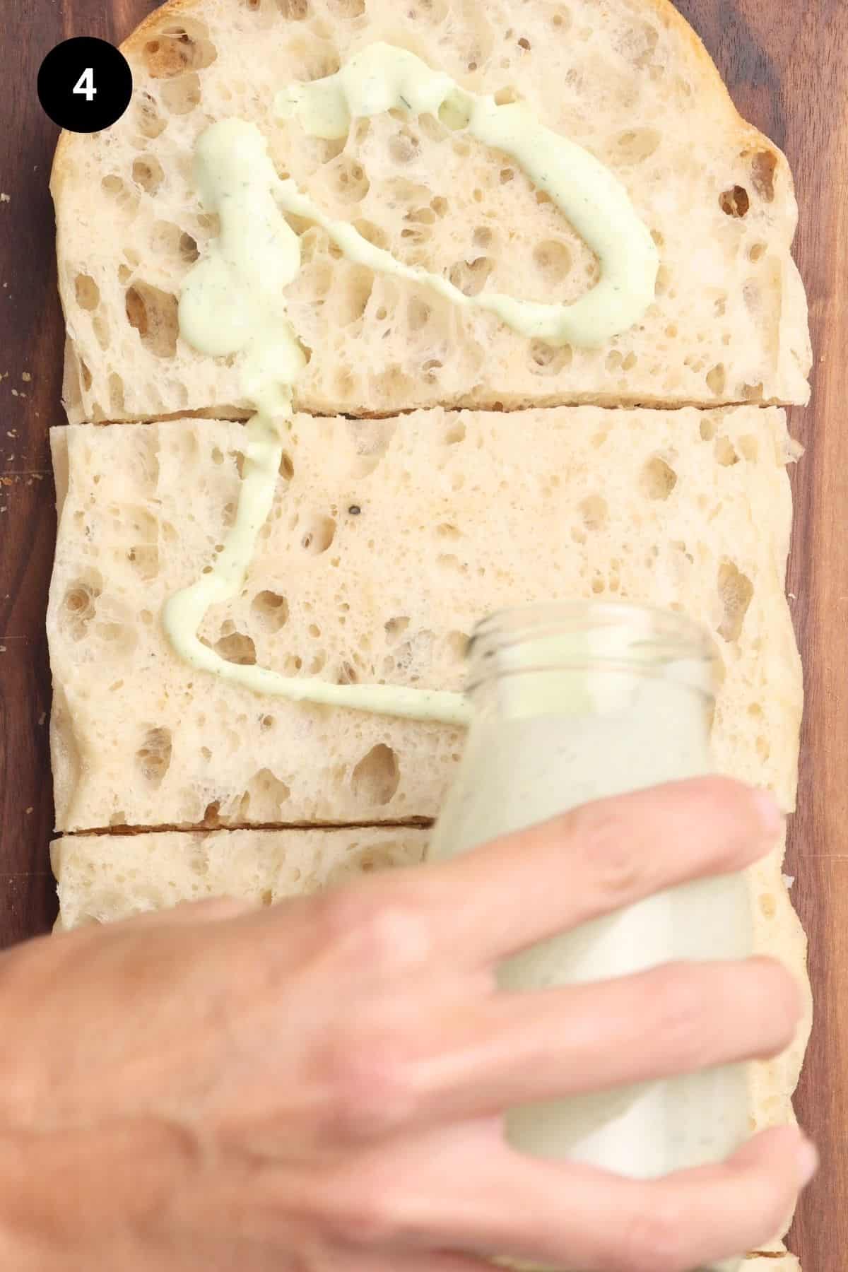 Ranch dressing being poured onto Turkish bread.
