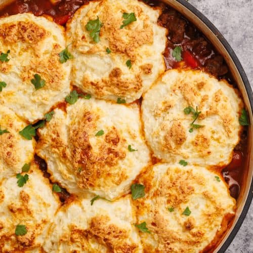 Cowboy casserole with biscuits in a Dutch oven.