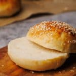Hamburger bun cut in half on a wooden board.