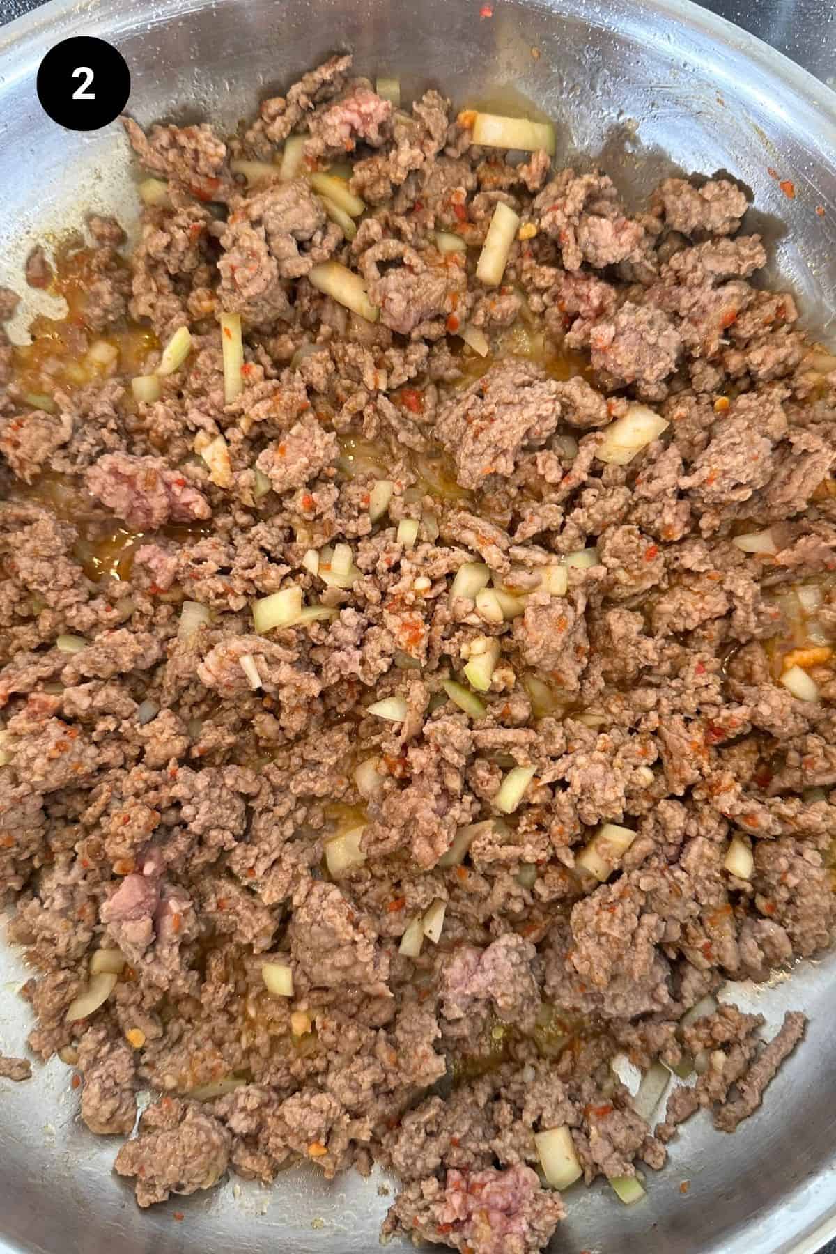 Browned ground beef with flavorings in a pan.