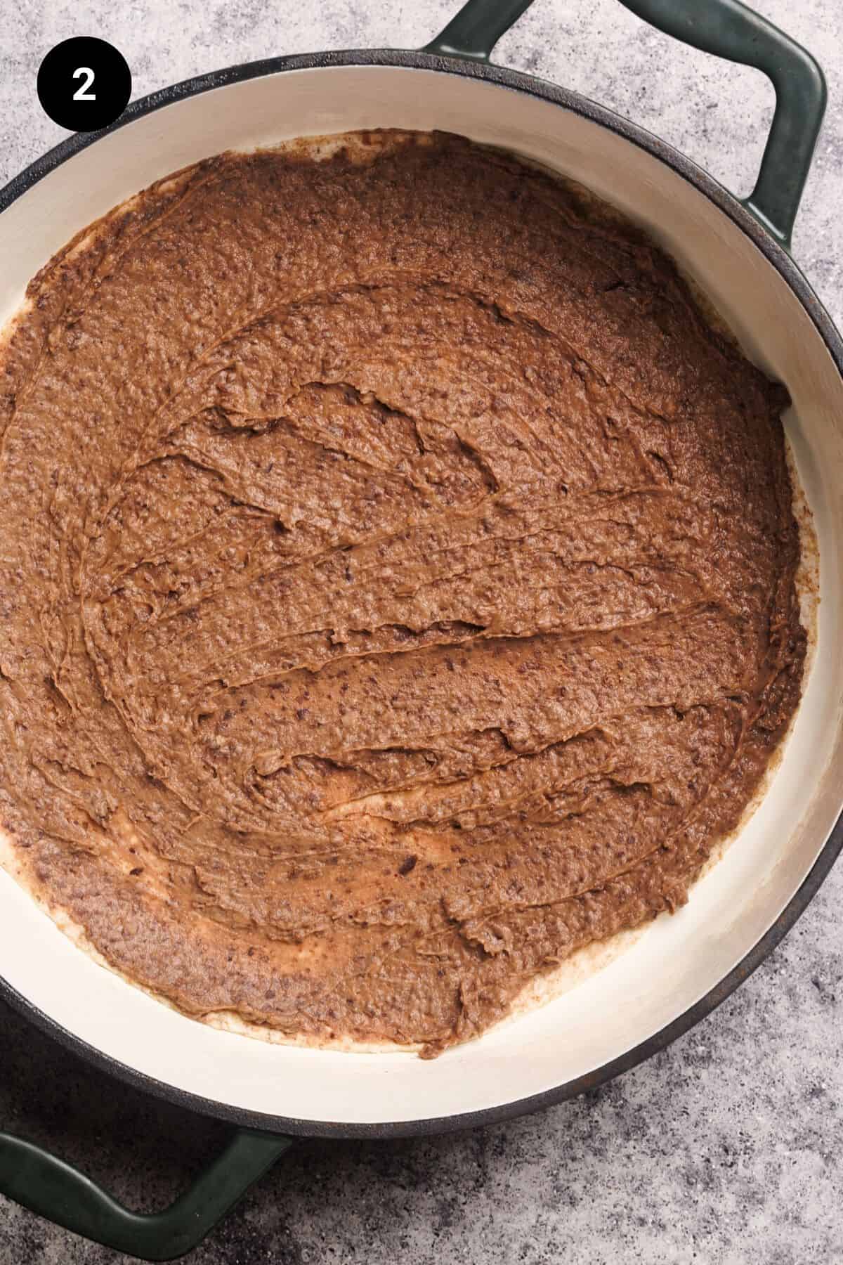 First refried beans and tortilla layer of the Mexican lasagna in a round casserole dish.