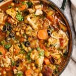 Moroccan chicken stew in a large Dutch oven next to a linen tea towel.