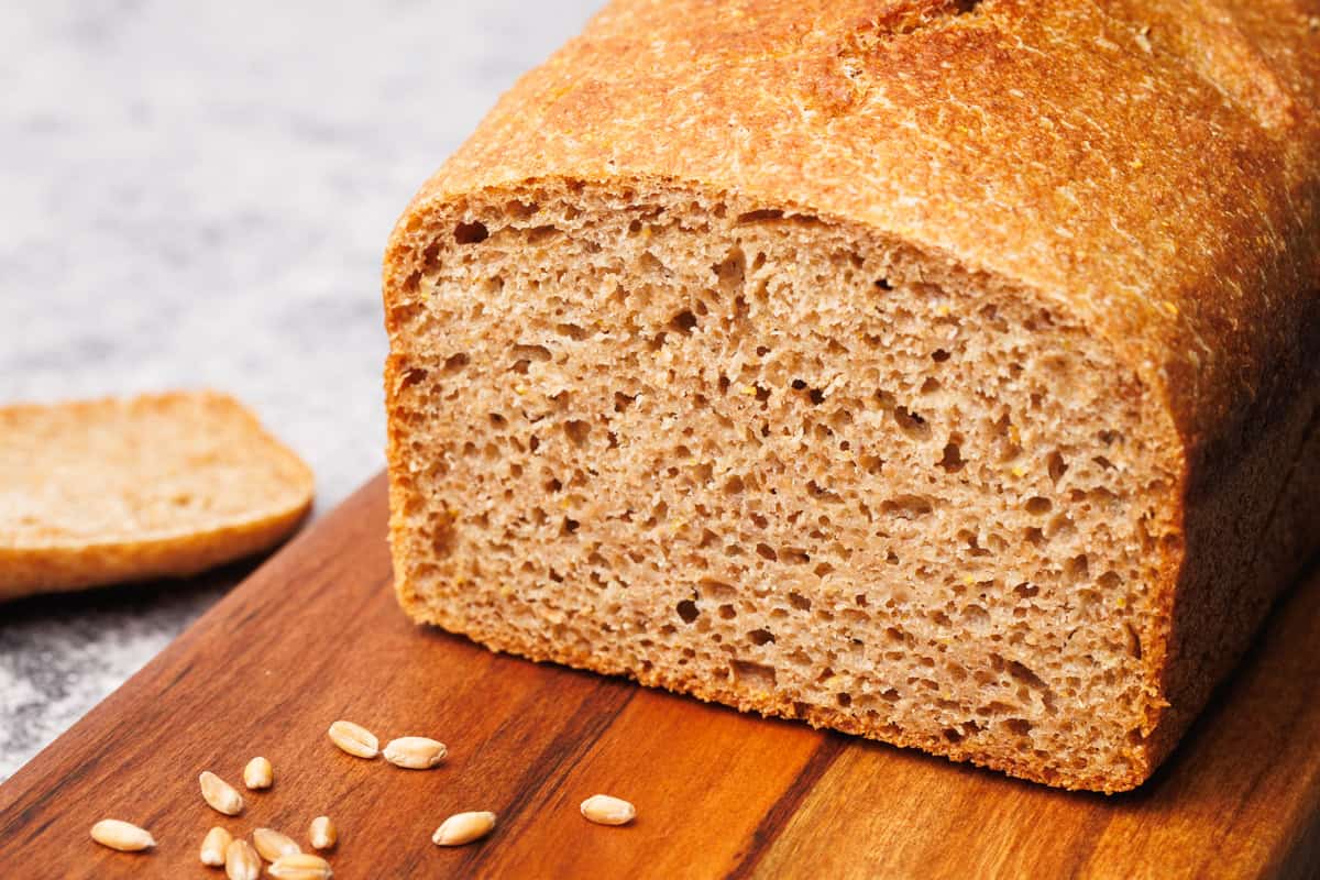 A loaf of whole grain spelt bread on a wooden board.