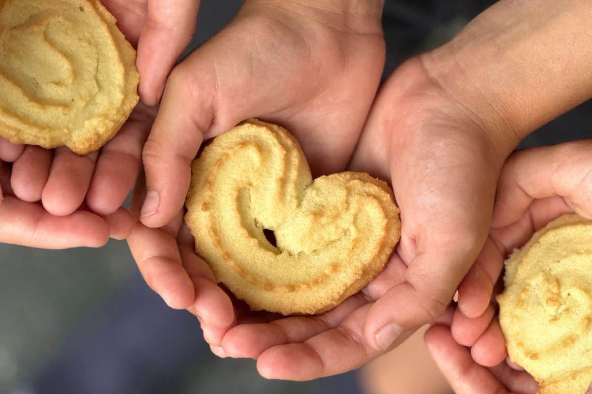 A child's hand holding a spritz cookie.