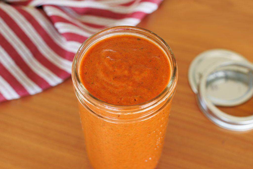 Romesco sauce in a mason jar on a wooden kitchen bench.