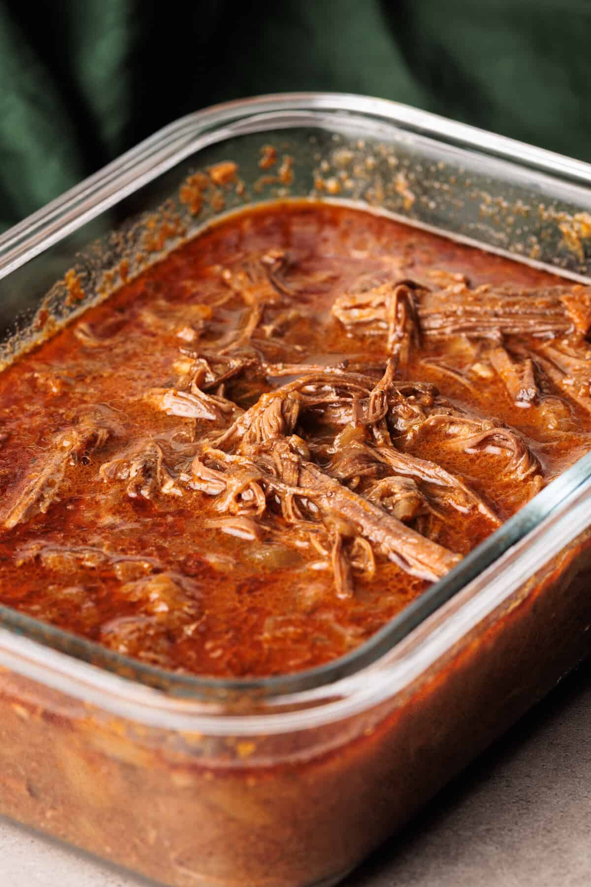 Beef barbacoa in a glass container.