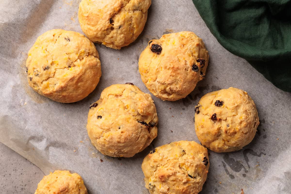 Spiced fruit bread rolls on parchment paper.